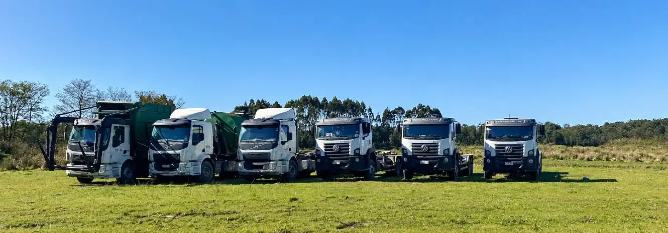 Seis camiones de la flota de retiro y transporte de residuos estacionados en un campo